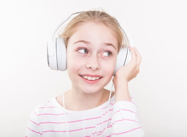 Menina sorridente feliz ouvindo música em fones de ouvido brancos . — Fotografia de Stock