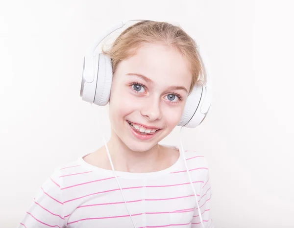 Lykkelig smilende barnejente lyttende musikk i hvite hodetelefoner . – stockfoto