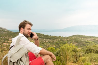 Bir cep telefonu tepeler arasında konuşan turist adam