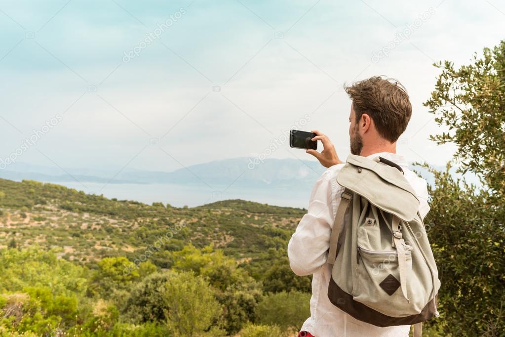 Tourist man takes a photo of beautiful landscape