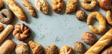 Fırın, farklı ekmek çeşitleri. Ekmek ruloları, baget, hamburgerler, çörekler ve kruvasan yukarıdan yakalanır. Boş kopya (metin) alanına sahip gri arkaplan.