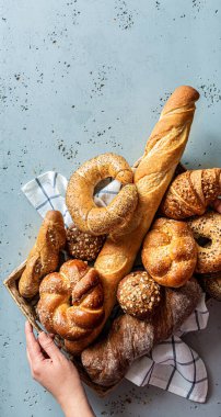 Fırın, tepside çeşitli ekmek parçaları var. Ekmek ruloları, baget, bagel, tatlı çörek ve kruvasan yukarıdan yakalanır (düz yatak). Boş kopya (metin) alanına sahip gri arkaplan.