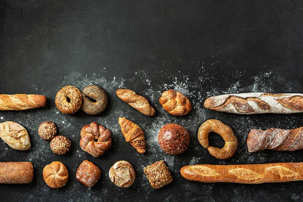 Fırın, çeşitli ekmek çeşitleri. Ekmek ruloları, baget, hamburgerler, çörekler ve kruvasan yukarıdan yakalanır. Boş kopya (metin) alanına sahip siyah yazı tahtası arkaplanı.