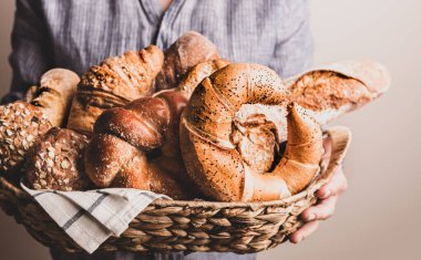 Fırın. Fırıncının elindeki kırsal tepside çeşitli ekmek parçaları var. Ekmek, baget, tatlı çörek ve kruvasan. Yakın çekim..