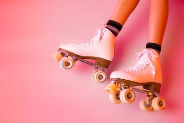 Retro classic white leather roller skates and girls legs - sports equipment and recreation. Pastel pink background. Layout with free copy space. clipart
