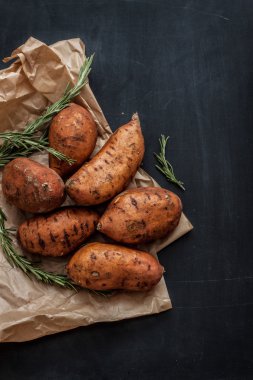 Sweet potatoes and rosemary on black chalkboard background