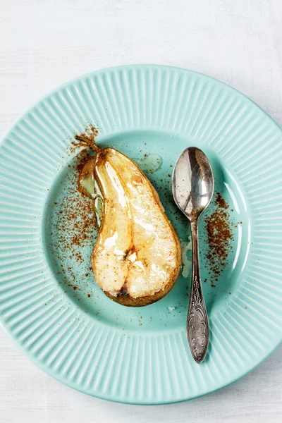 Caramelized pear with cinnamon and vintage spoon on pastel blue plate