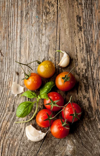 Cherry tomatoes, garlic and fresh basil on vintage wooden table — Stok fotoğraf