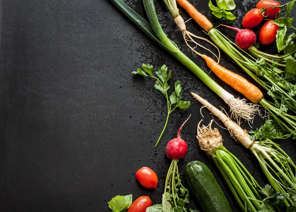 Young spring vegetables on black chalkboard