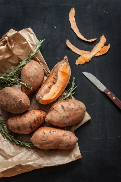 Descascando batatas doces com faca no quadro preto — Fotografia de Stock