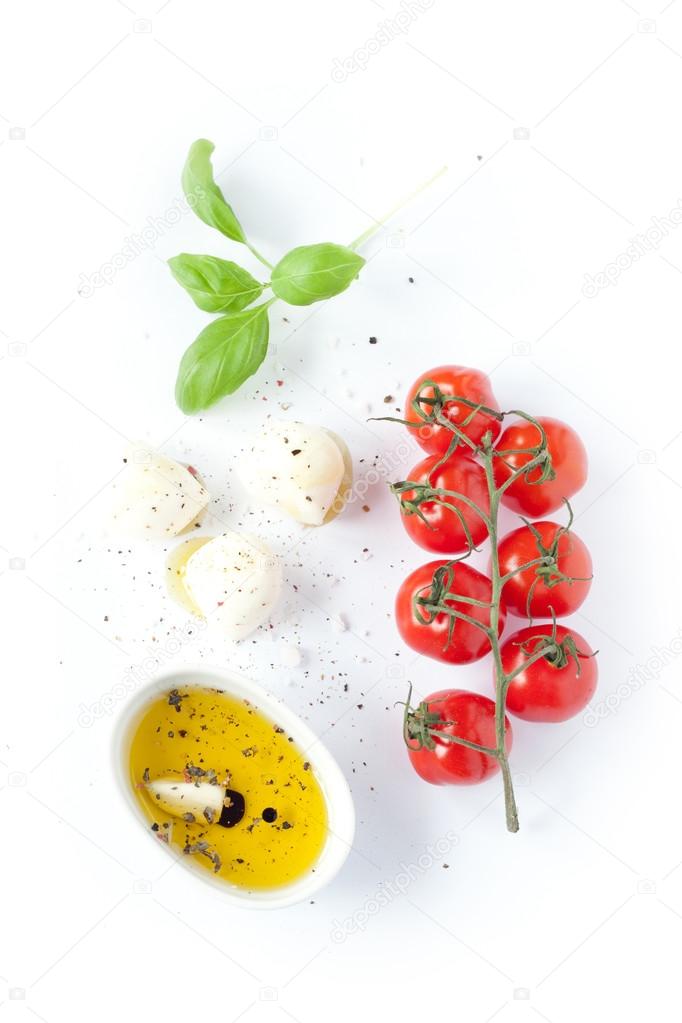 Cherry tomatoes, mozzarella cheese, basil and olive oil on white