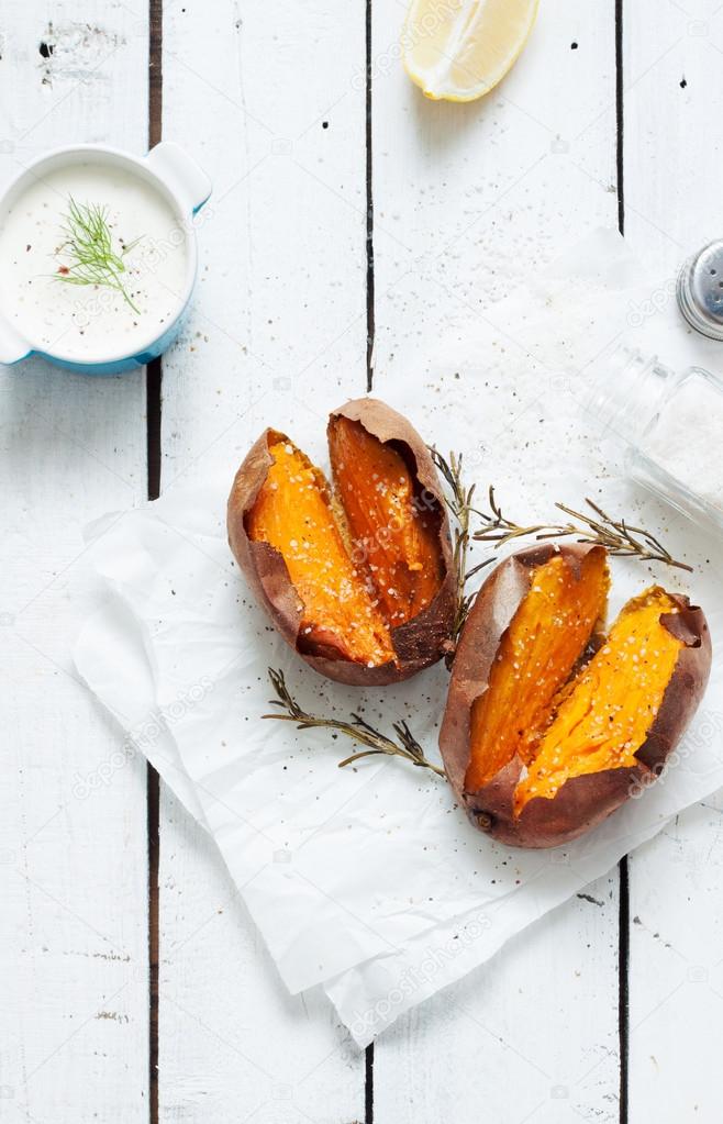 Baked sweet potatoes, dip, salt and rosemary on white wood rustic picnic table