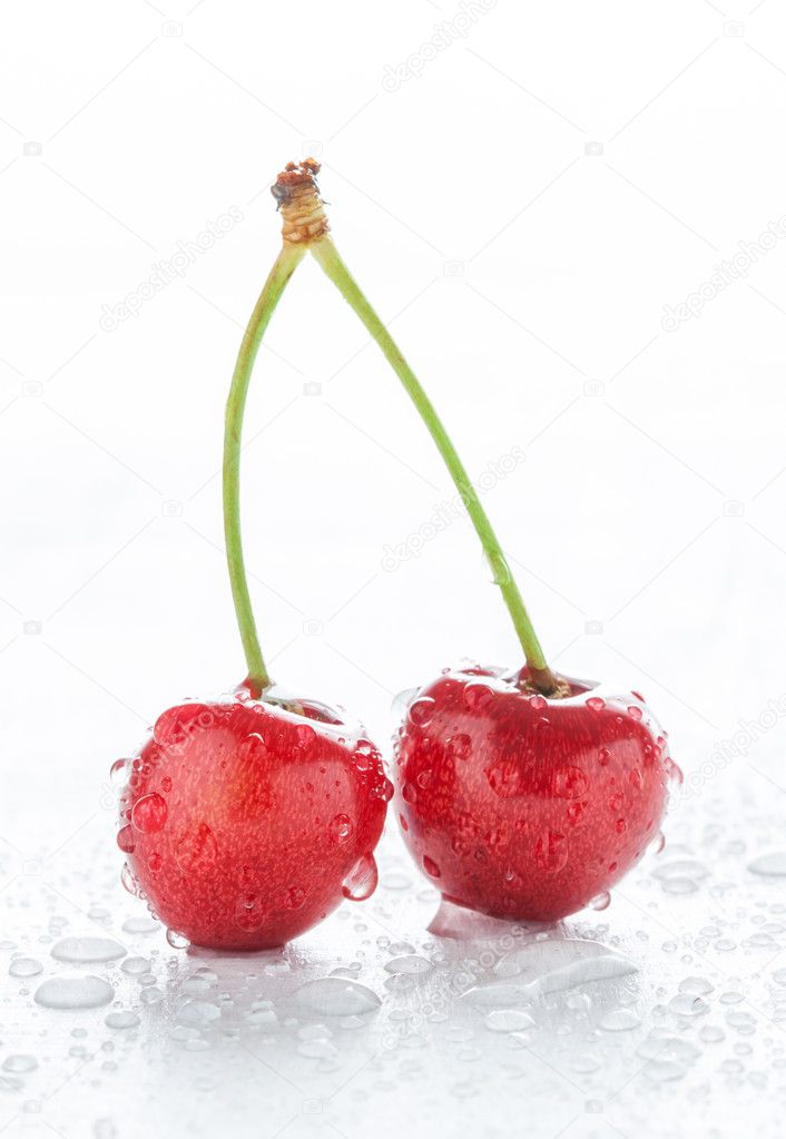 Two cherries with water drops on white wet table