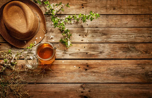 Paese - vaso di miele, cappello da giardiniere e ramo d'albero in fiore — Foto Stock