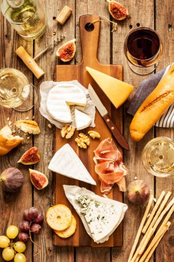 Different kinds of cheeses, wine, baguette, fruits and snacks clipart