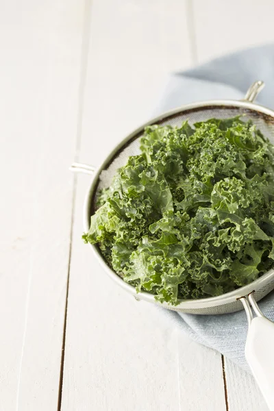 Fresh wet kale in a sieve on white planked wooden table — Stok fotoğraf