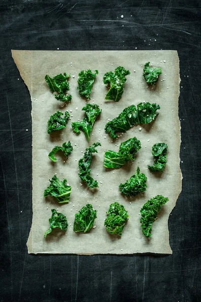 Kale bits on baking paper - preparing kale chips — Stock Photo, Image