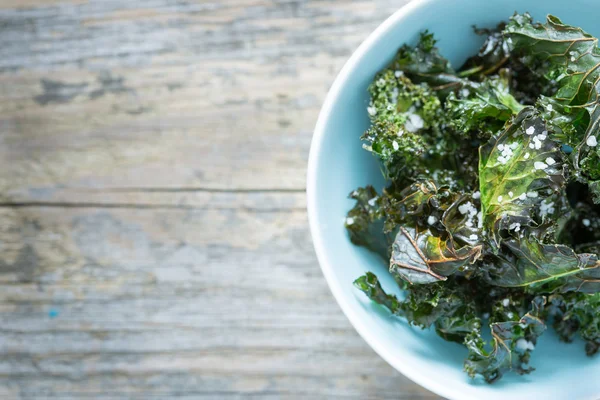 Kale chips with salt in pastel blue bowl — Stock Photo, Image