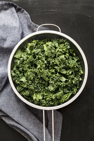 Fresh wet kale in a sieve and grey napkin on black — Φωτογραφία Αρχείου