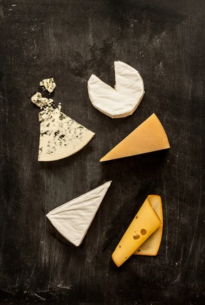 Different kinds of cheeses on black from above