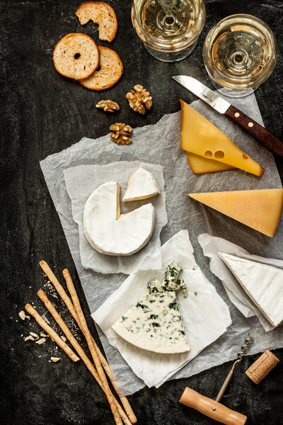Different kinds of cheeses, white wine and snacks