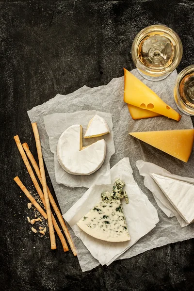 Различные виды сыров, белого вина и закусок — стоковое фото
