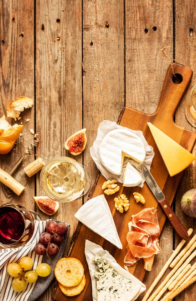 Diferentes tipos de queijos, vinho, baguetes, frutas e lanches — Fotografia de Stock