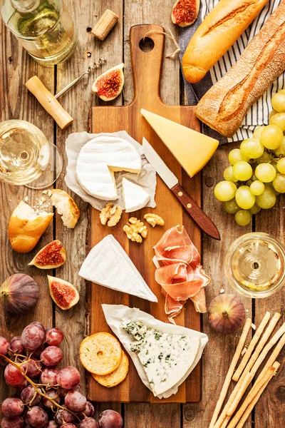 Different kinds of cheeses, wine, baguette, fruits and snacks — Stock Fotó