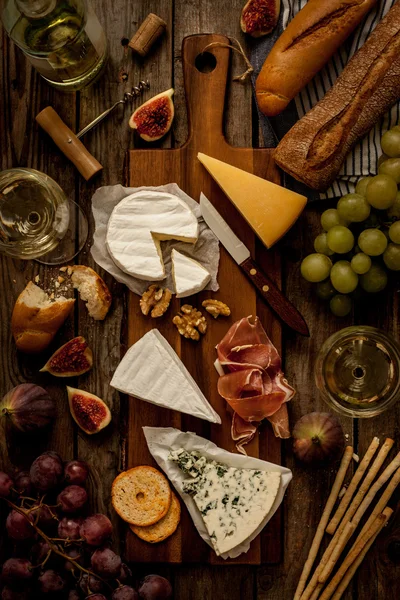 Different kinds of cheeses, wine, baguettes, fruits and snacks — Stock fotografie