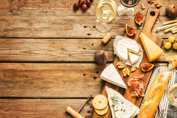 Different kinds of cheeses, wine, baguettes, fruits and snacks