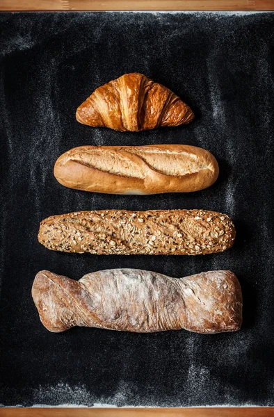 Different kinds of bread rolls on black from above