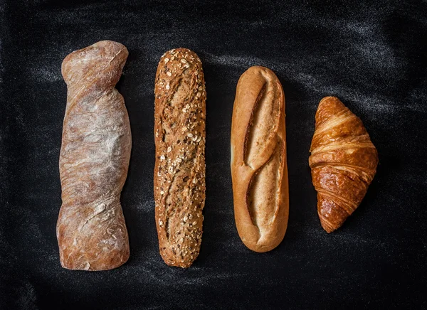 Different kinds of bread rolls on black from above — Stock Photo, Image