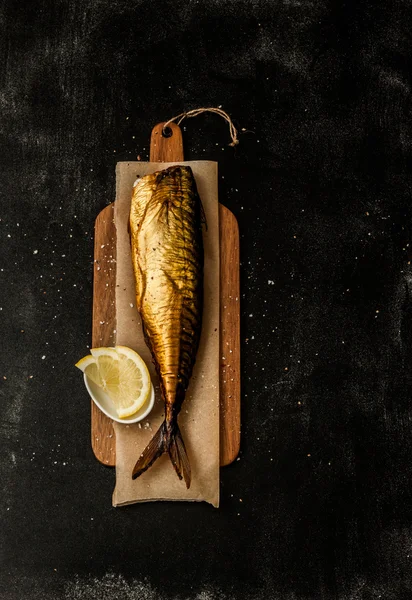 Smoked mackerel and lemon slices on black from above