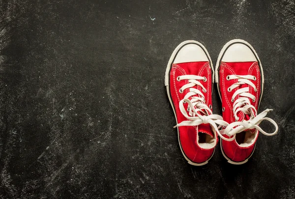 Red sneakers on black chalkboard from above — Stockfoto