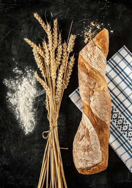 Frans stokbrood, tarwe en meel op zwart — Stockfoto
