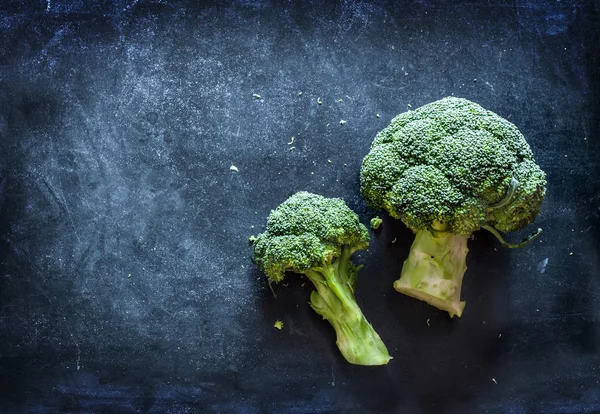Raw broccoli on black chalkboard - top view — Stock Photo, Image