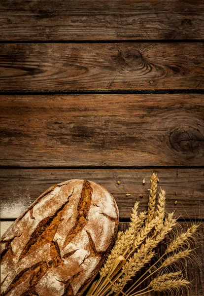 Pan rústico y trigo en una antigua mesa de madera vintage — Foto de Stock