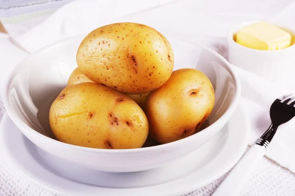 Boiled jacket potatoes served in a white bowl with butter — Stock Photo, Image