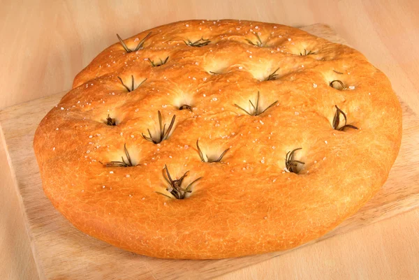 Frisch gebackenes Foccacia-Brot mit Rosmarin auf einem Holzbrett — Stockfoto