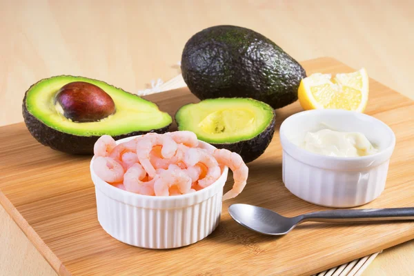 Ahşap pla üzerinde avokado ve beyaz soslu soyulmuş karides pişmiş