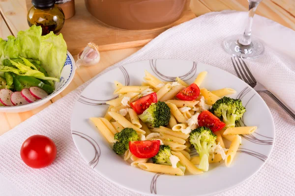 Pasta penne with broccoli, tomatoes and mozzarella served on a p — Stock Photo, Image