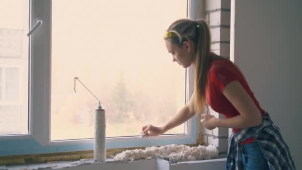 Pretty girl cleans frame of new window in empty apartment — Stock Footage Pretty girl cleans frame of new window in empty apartment Stock Video