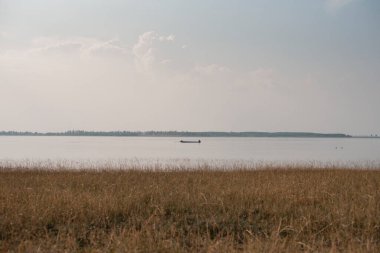 Su deposunun ortasında, uzak bir adaya bakan küçük bir tekne..