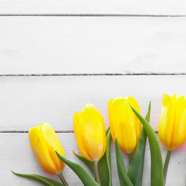Желтые тюльпаны на деревянной поверхности — стоковое фото