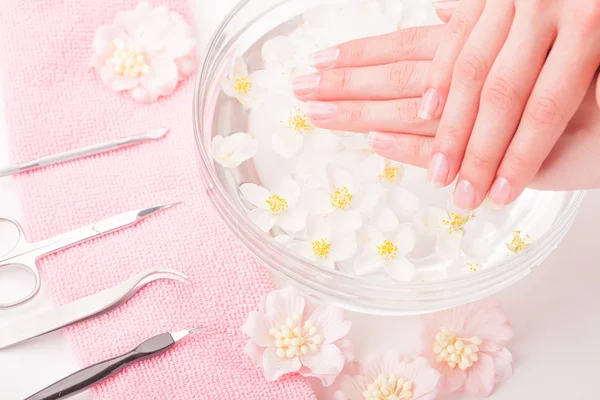 Mooie dames handen met manicure in kom met water — Stockfoto