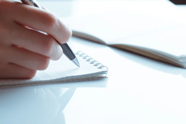 Womans hand writing entries in a notebook — Stock Photo, Image