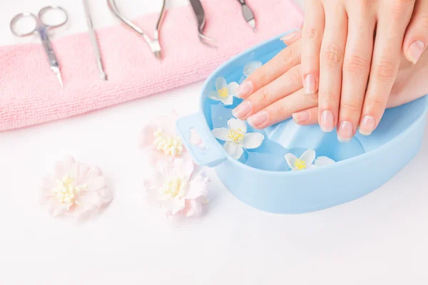 Mooie dames handen met manicure in kom met water — Stockfoto