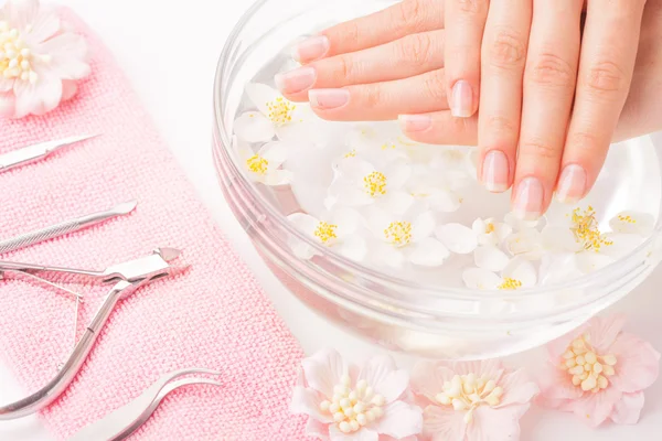 Mooie dames handen met manicure in kom met water — Stockfoto