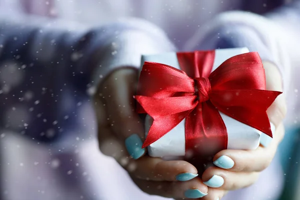 Caja de regalo con lazo rojo en manos de mujer — Foto de Stock