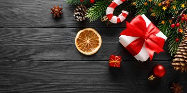 Siyah ahşap arka planda noel süslemesi olan hediye kutusu.